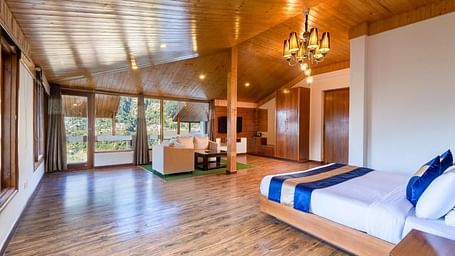 Image of a  suite with a wooden ceiling, walls, and floors, featuring a king size bed and a sitting area  | DLS Serenity Resort and Spa